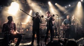 Calexico, 2015-04-25 on stage at "Den Atelier", Luxembourg. From left to right: Jairo Zavala, John Convertino, Jacob Valenzuela, Martin Wenk, Sergio Mendoza, Joey Burns, Ryan Alfred. Auteur: Zippo Zimmerman. (Wikimedia, CC BY-SA 4.0)