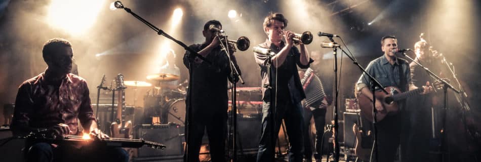 Calexico, 2015-04-25 on stage at "Den Atelier", Luxembourg. From left to right: Jairo Zavala, John Convertino, Jacob Valenzuela, Martin Wenk, Sergio Mendoza, Joey Burns, Ryan Alfred. Auteur: Zippo Zimmerman. (Wikimedia, CC BY-SA 4.0)